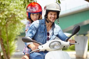 Happy young couple riding a scooter in the city on a sunny day